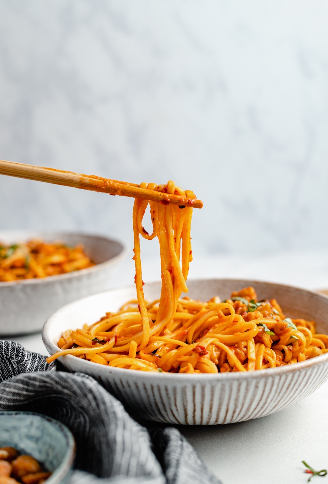 pulling spicy chicken ramen noodles up out of a bowl with chopsticks