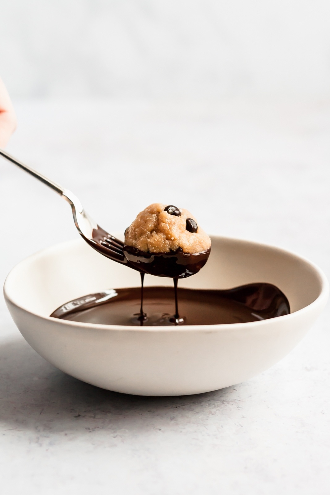 dipping a vegan cookie dough bite in chocolate