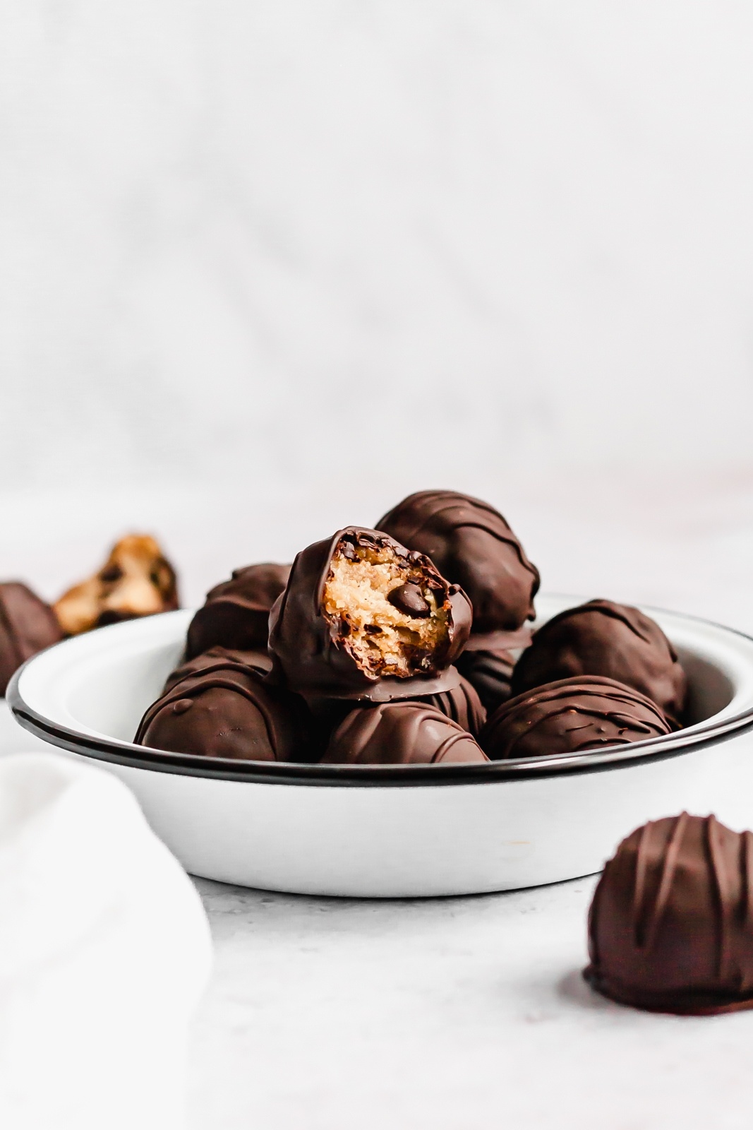 tahini cookie dough bites in a bowl with a bite taken out of one