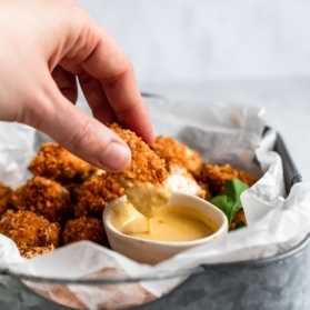 dipping a crispy baked chicken nugget in honey mustard