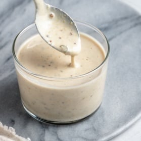 spooning vegan caesar dressing out of a jar