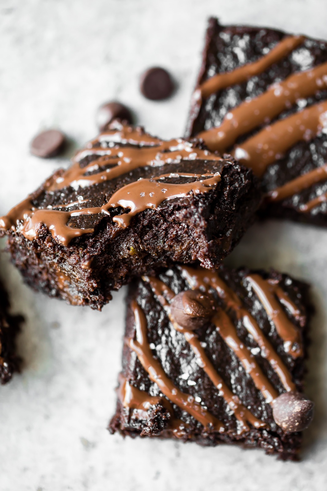 three healthy zucchini brownies drizzled with chocolate and stack on top of each other