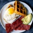 zucchini cornbread waffles on a plate with egg, avocado, and turkey bacon