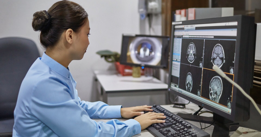Side view of female radiologist examining X-ray images on computer.